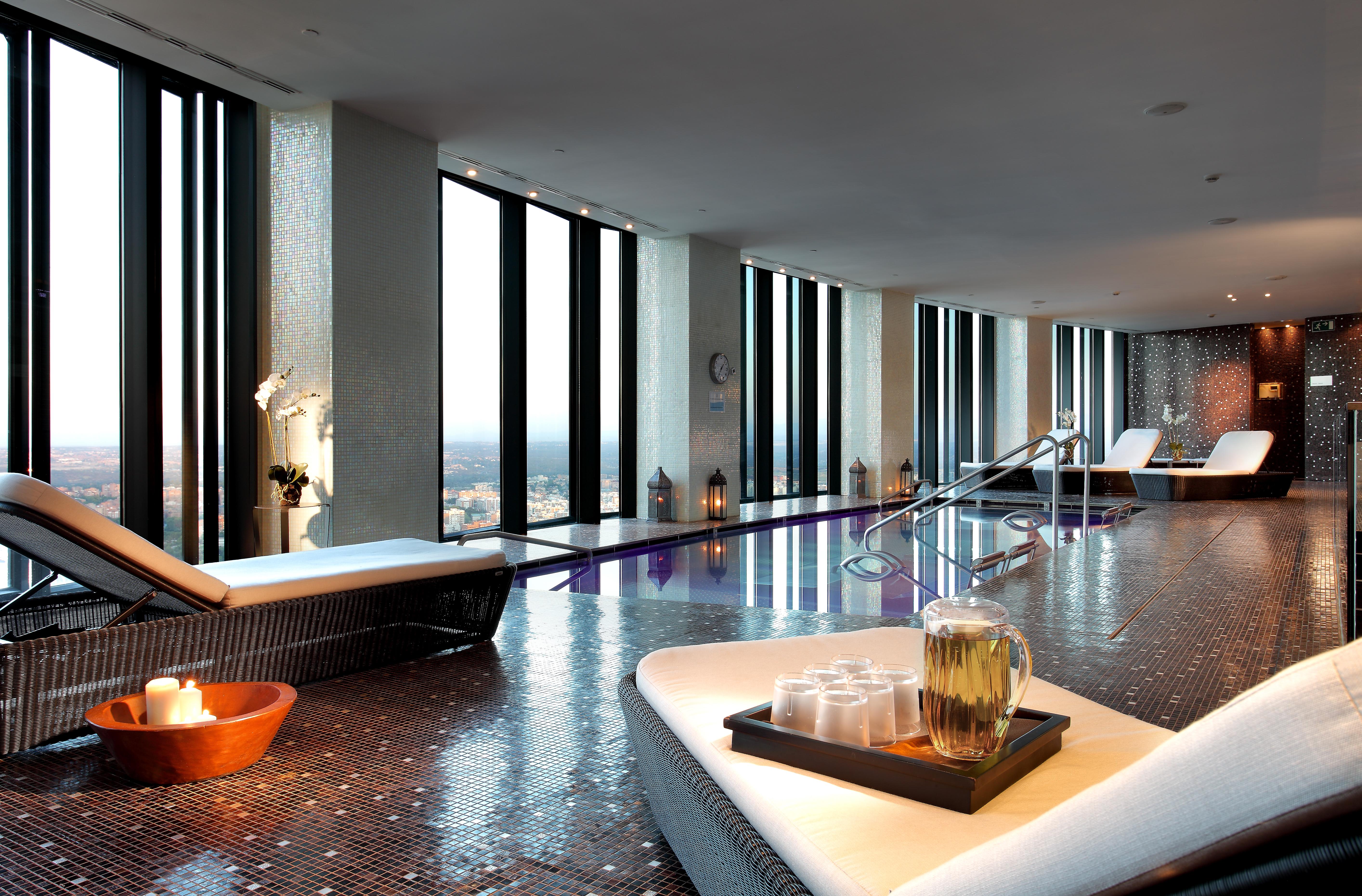 Eurostars Madrid Tower Hotell Eksteriør bilde The photo depicts a luxurious spa interior with large windows that offer a panoramic view of the outside. The space features sleek, modern lounge chairs and a tranquil atmosphere. There is a pool area, and the floor is tiled with reflective materials