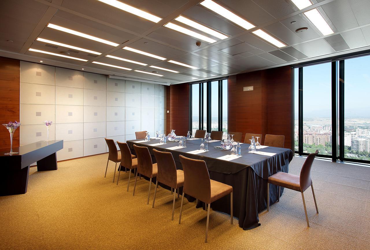 Eurostars Madrid Tower Hotell Eksteriør bilde The photo shows a modern conference room with a long table set up for meetings. There are several chairs around the table, and the table is covered with a dark tablecloth. On the table, there are glass pitchers and cups, indicating it is prepared for