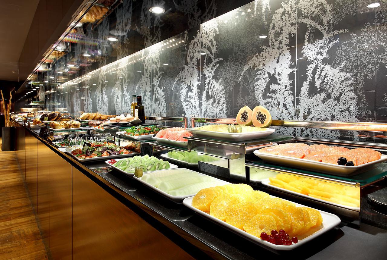 Eurostars Madrid Tower Hotell Eksteriør bilde The photo shows a buffet display featuring a variety of dishes and ingredients. There are plates filled with different types of food, including seafood, fruits, and vegetables. The arrangement is visually appealing, with the food presented on glass s