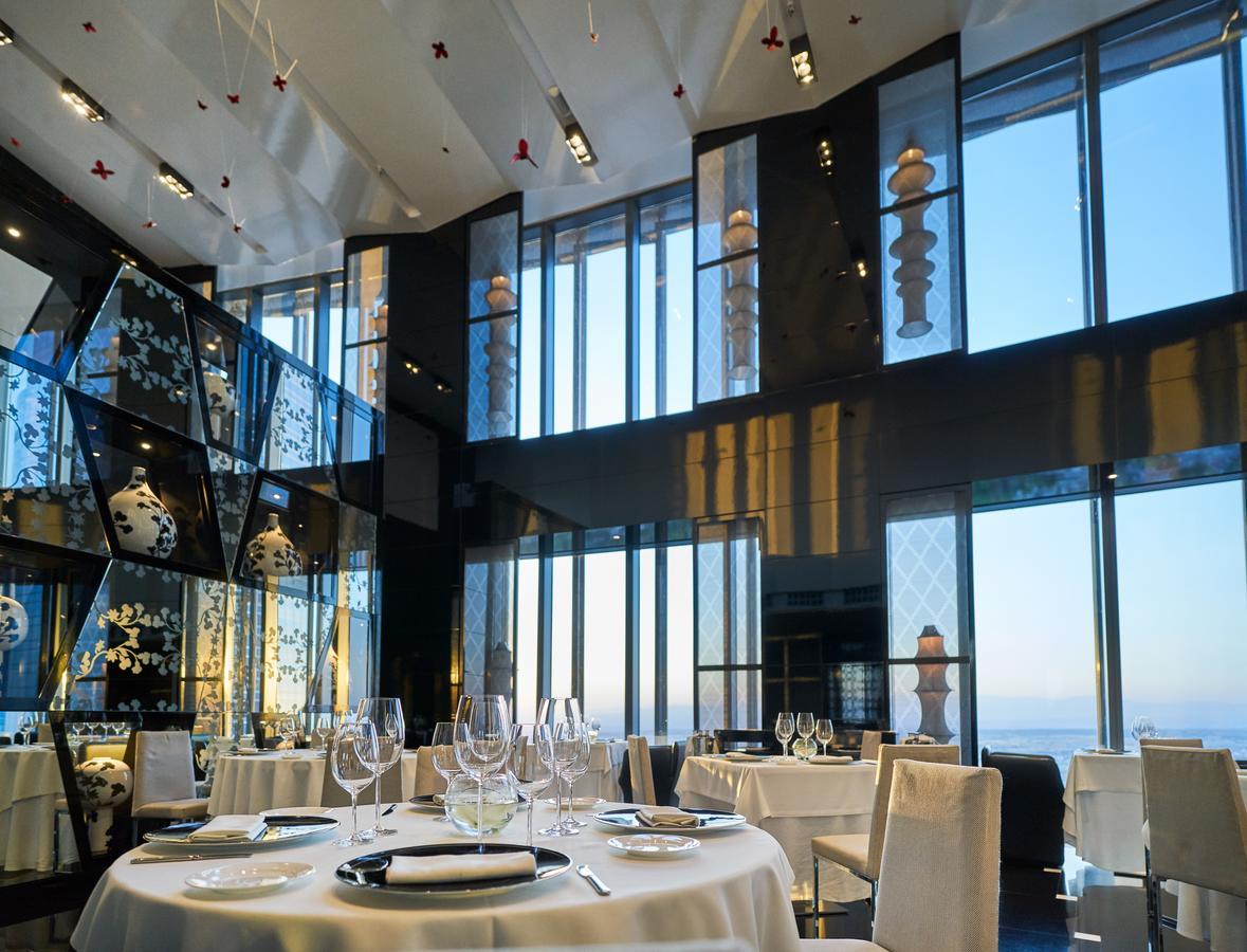 Eurostars Madrid Tower Hotell Eksteriør bilde The photo shows an elegant restaurant interior featuring a modern design. The space has large windows that provide a view of the outside, allowing natural light to fill the room. The decor includes artistic elements, such as sculptures and decorative